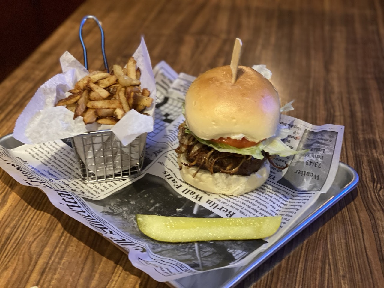 A burger and a basket of fries served on newsprint at Obal's Inn